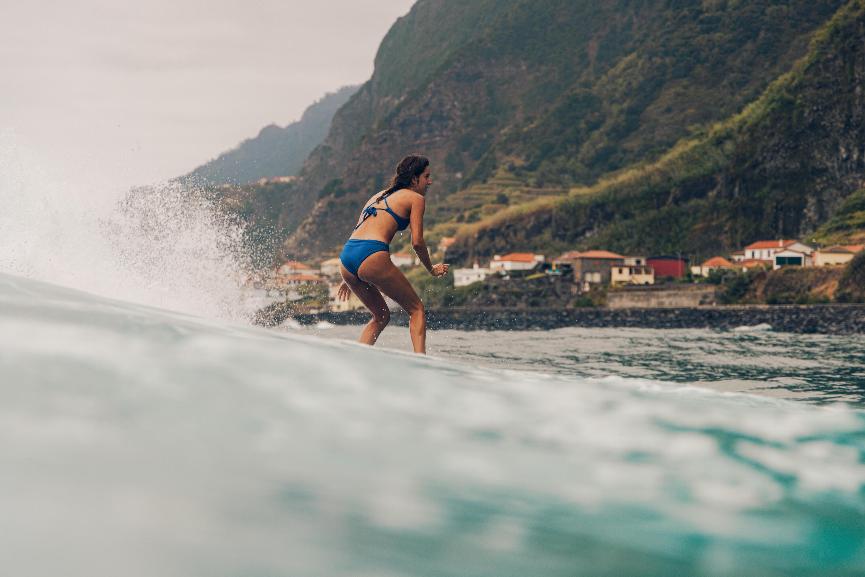 Surfista remando hacia una ola con su tabla y traje de neoprene en una playa oceánica