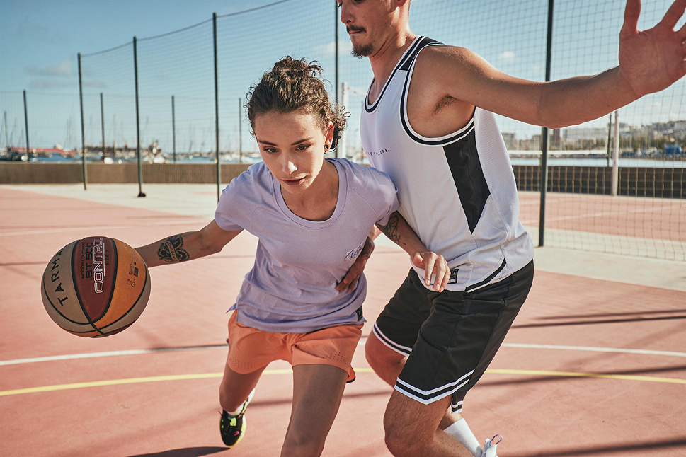 Jugador de básquet realizando un lanzamiento al aro con una pelota técnica en un gimnasio techado